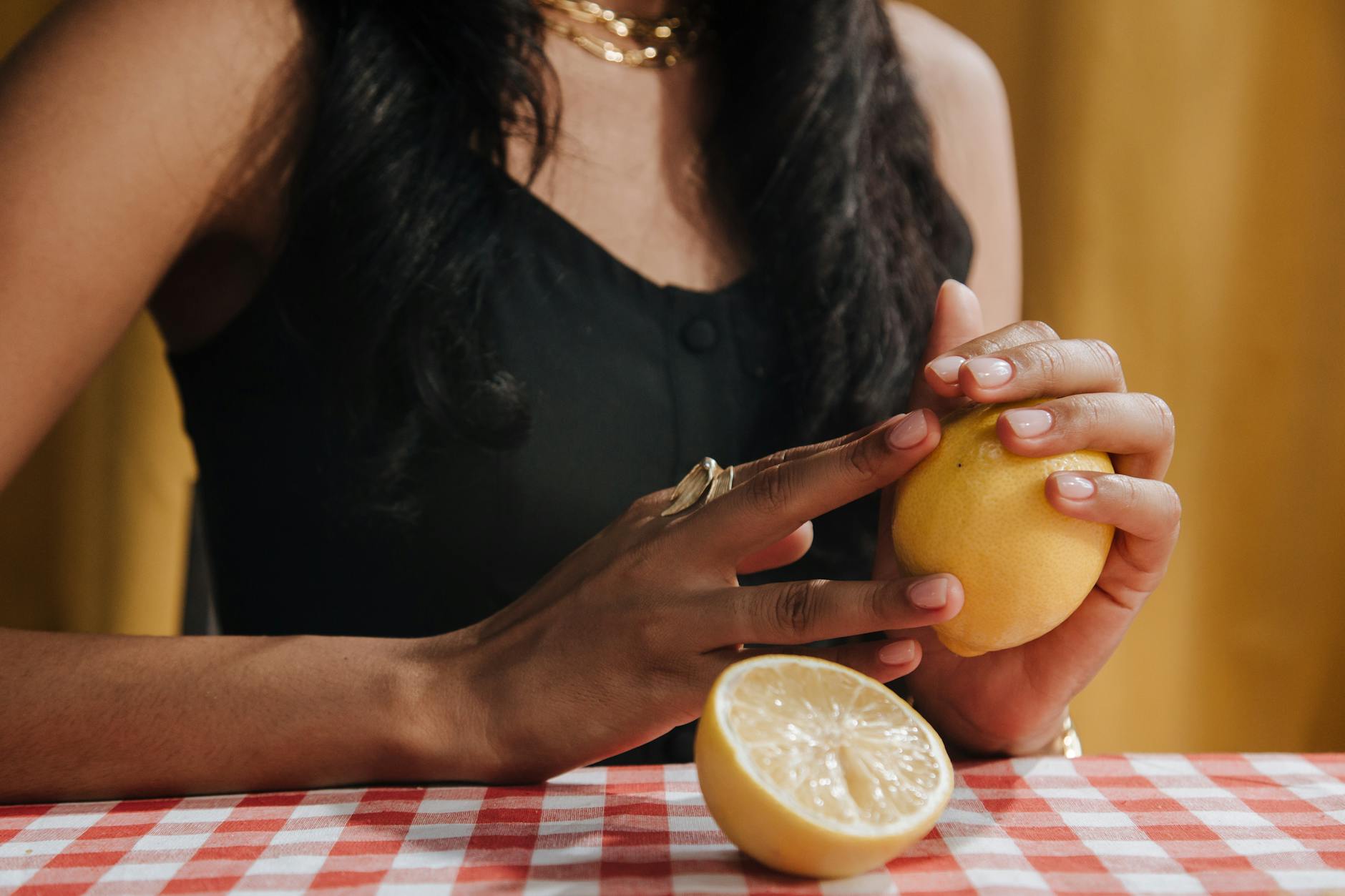 Una donna che tiene in mano un limone fresco su un tavolo da pranzo