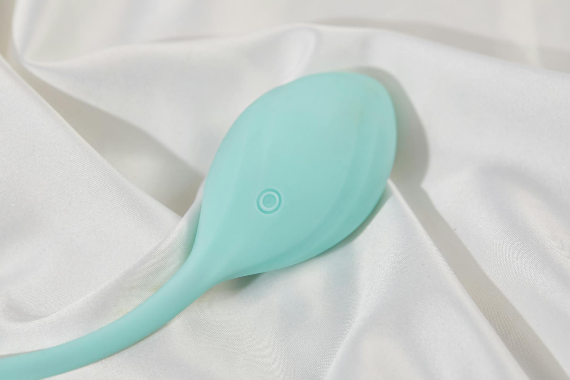 Un vibratore colorato disposto su tessuto di seta, simbolo di scelta ponderata e intenzionalità adulta