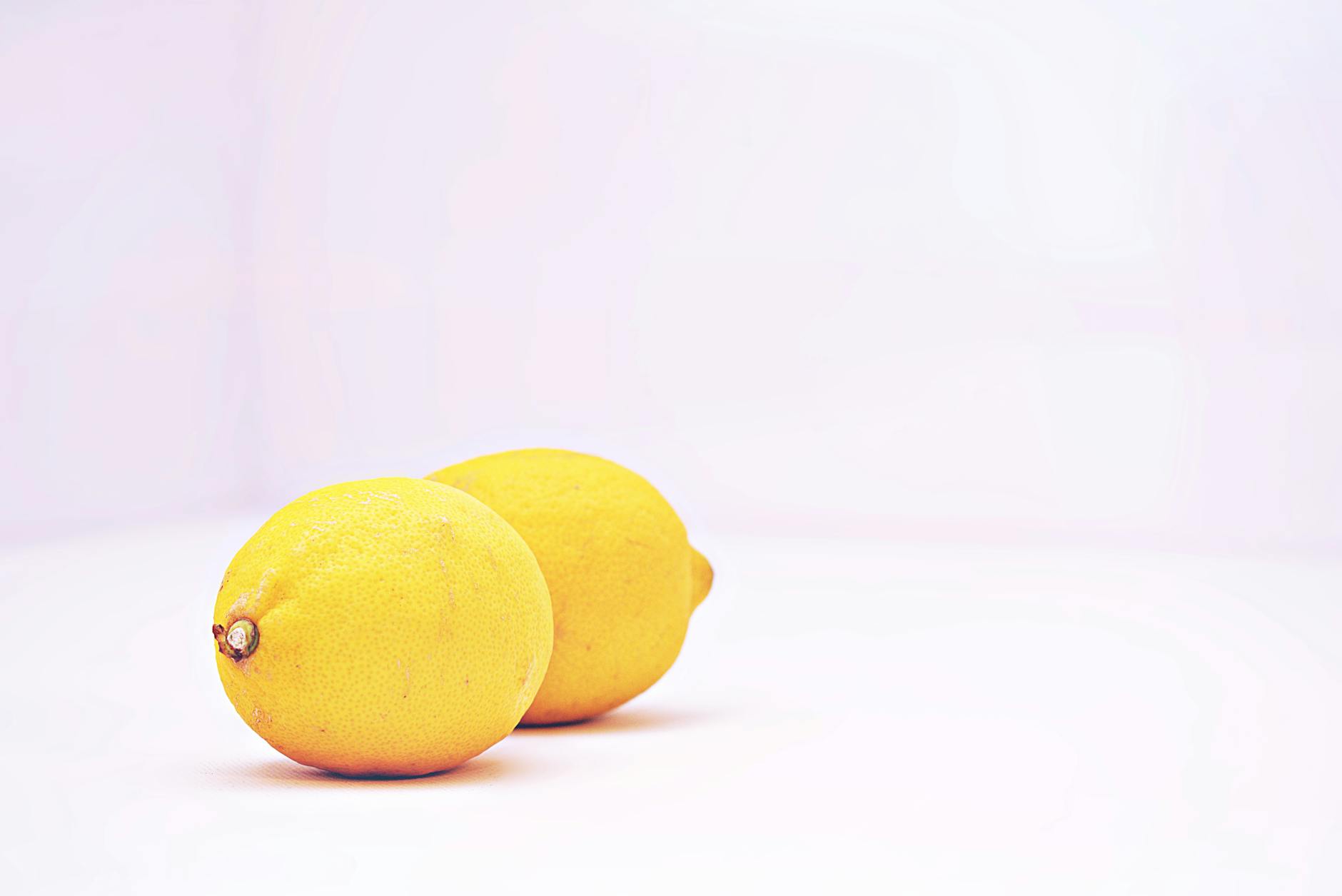 Una mano che tiene un limone fresco su uno sfondo giallo vivace, che trasmette freschezza e rinascita