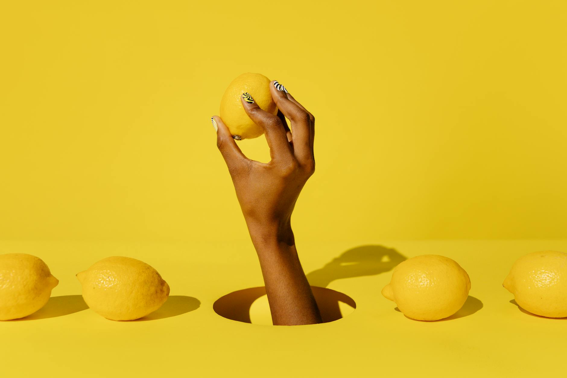 Una mano tiene un limone fresco su uno sfondo giallo vivido, simboleggiando la freschezza e l'energia dei vibratori al limone