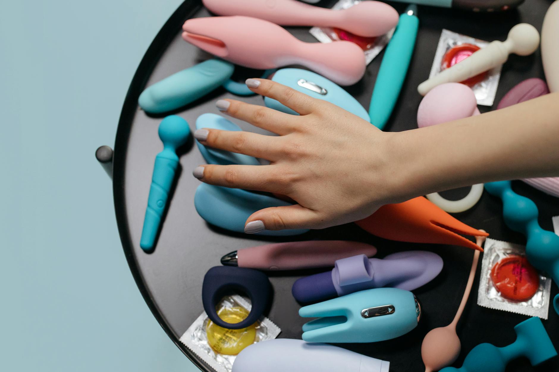 Una mano che tiene un vibratore blu in silicone su uno sfondo viola, simboleggiando l'amore per se stessi e la sessualità consapevole