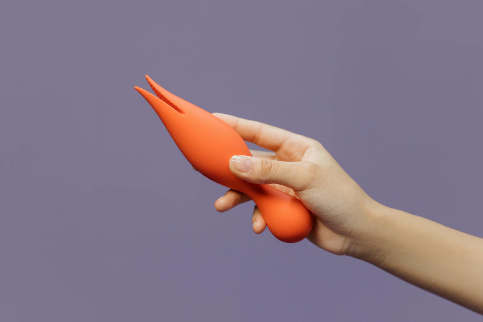 Una mano tiene un vibratore contro uno sfondo minimalista, mostrando la sensualità moderna.