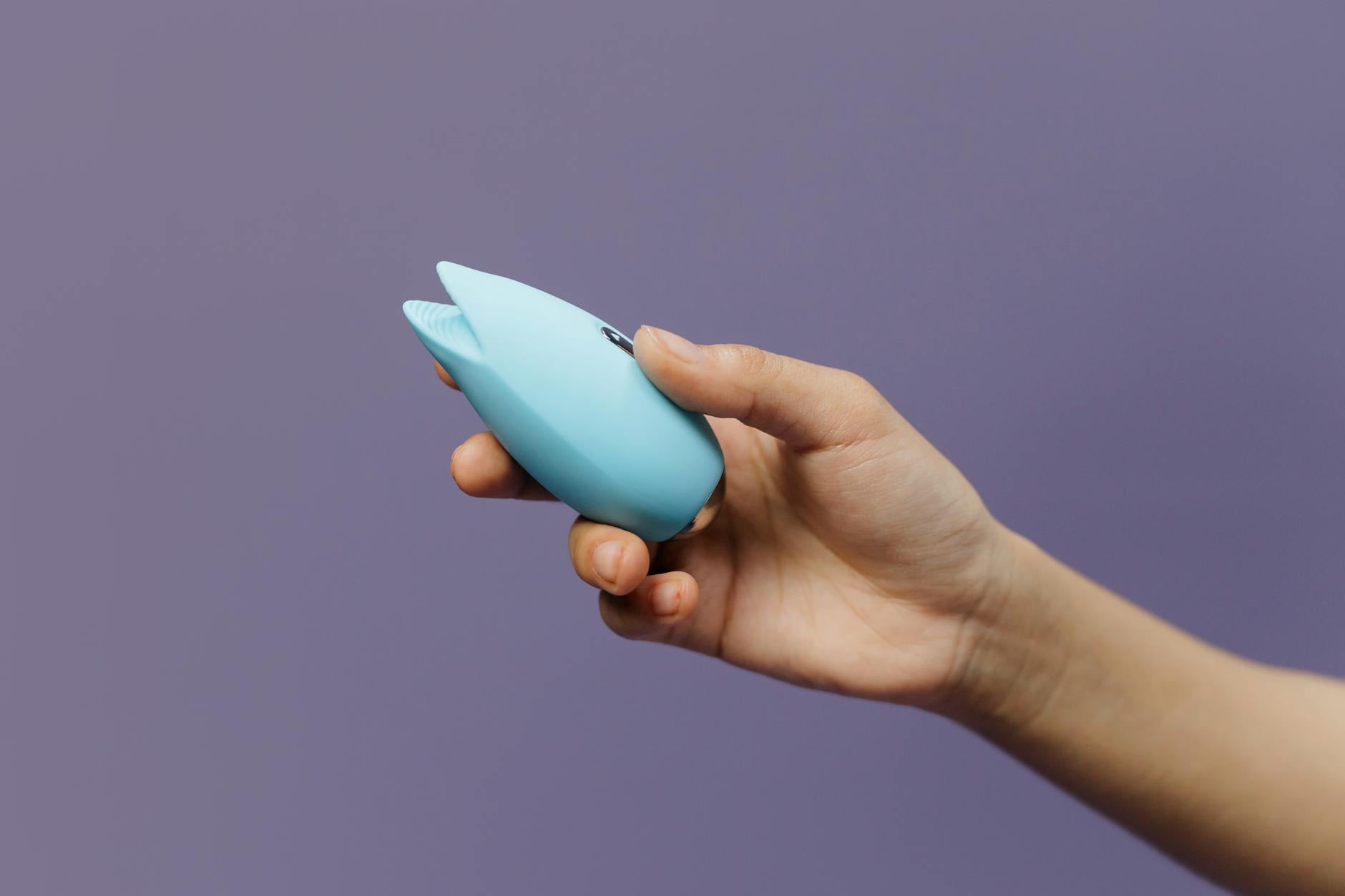 Un vibratore al limone blu tenuto in mano su sfondo viola, promozionando l'auto-amore e la sessualità.