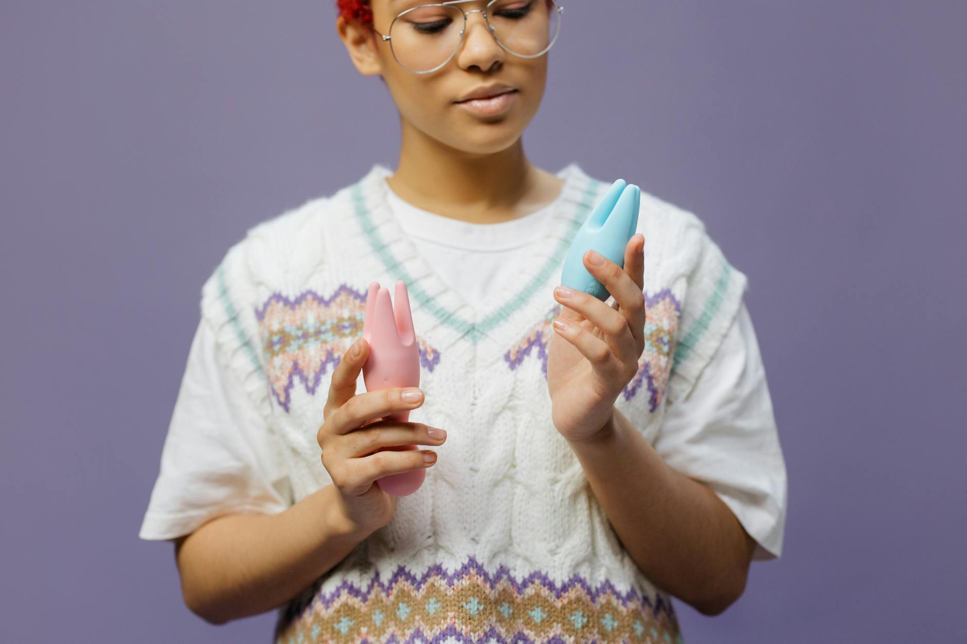 Donna che tiene in mano vibratori colorati in silicone blu e rosa in modo contemplativo