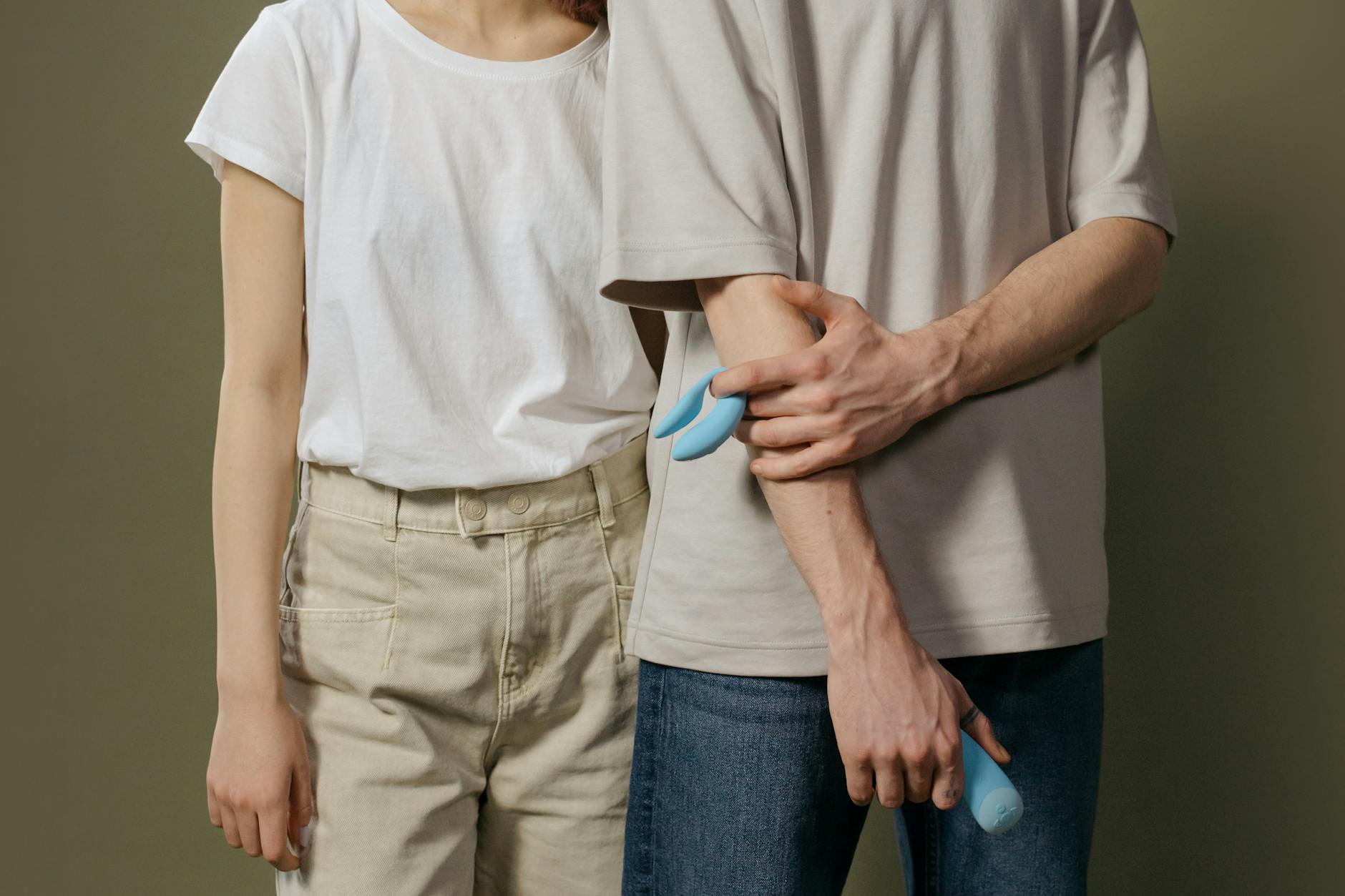 Donna con occhiali che tiene in mano vibratori in silicone blu e rosa, in un momento di consapevolezza intima.