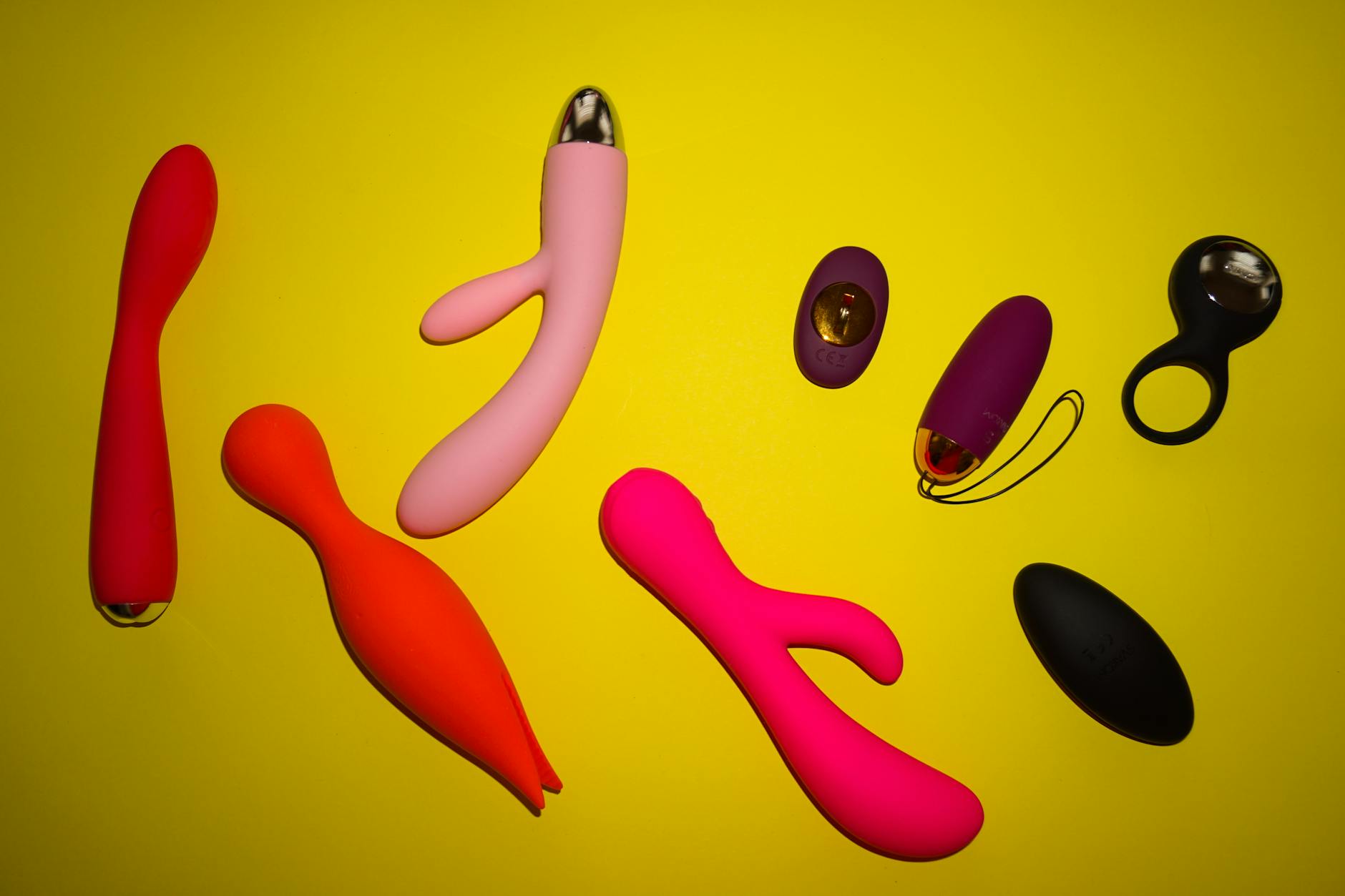 Vibrant arrangement of colorful adult toys on bright yellow surface showcasing design diversity